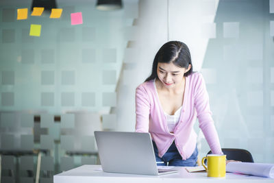 Young woman using phone while sitting on table