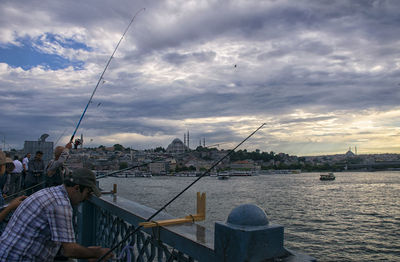 Man fishing in river against sky