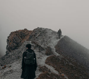 Rear view of man standing on mountain against clear sky