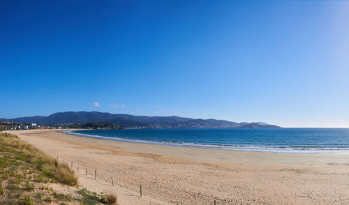 Scenic view of beach against clear blue sky