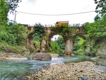 Arch bridge over river against sky