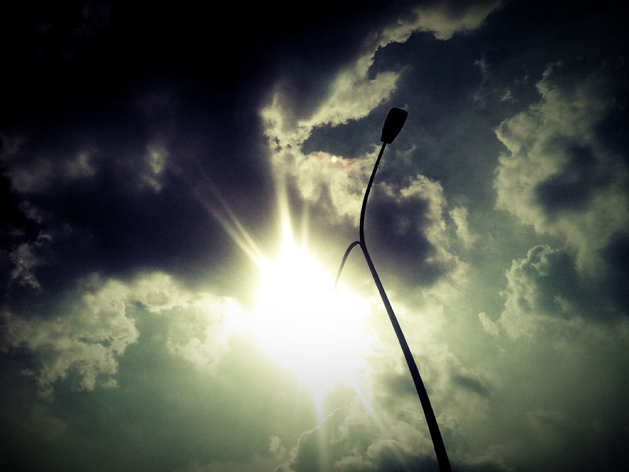 low angle view, sun, sky, sunbeam, cloud - sky, lens flare, sunlight, silhouette, cloudy, street light, bright, cloud, nature, electricity, back lit, beauty in nature, outdoors, lighting equipment, no people, glowing