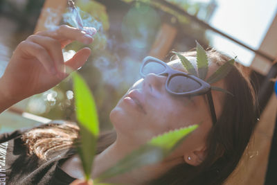 Close-up of woman holding marijuana joint by plant