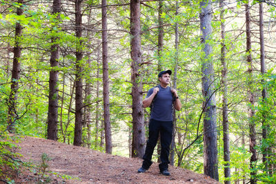 Mature man standing against trees at forest