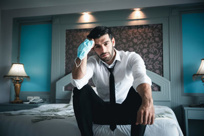 Young man sitting on bed at home