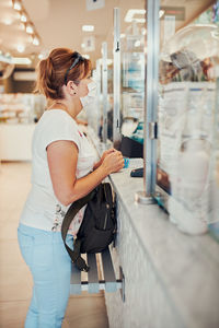 Mature woman wearing mask standing in cafe