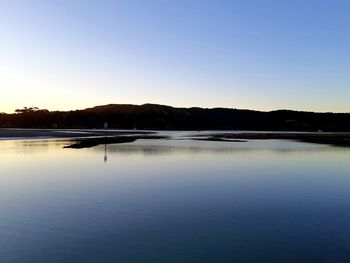 Scenic view of lake against clear sky during sunset