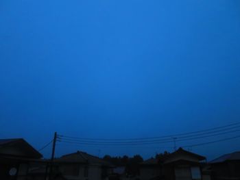 Low angle view of silhouette buildings against clear blue sky