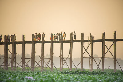 People standing by railing against clear sky