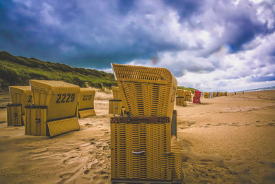 Hooded beach chairs on sand against sky