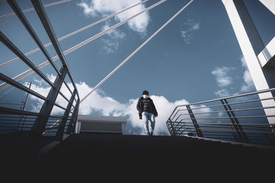 Low angle view of woman standing on staircase against sky