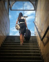 Low angle view of woman on staircase against sky