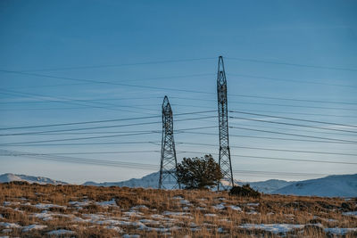 Electricity pylon on land against sky during winter