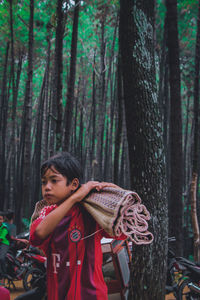 Woman standing by tree trunk in forest