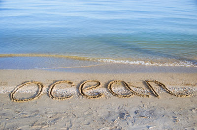 High angle view of ocean text on sand at beach