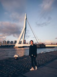 Portrait of man standing against bridge over river in city