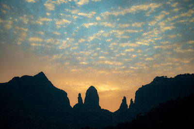 Silhouette rock formations against sky during sunset