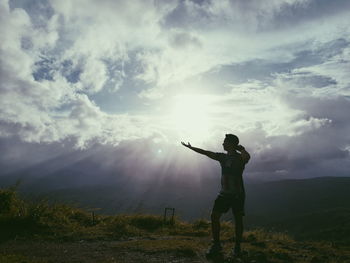 Rear view of man standing on field against sky