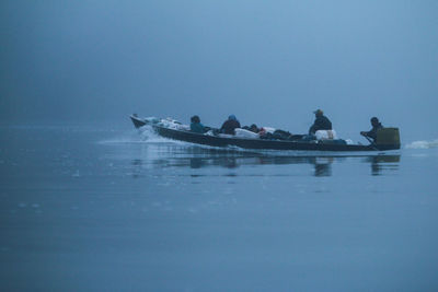 People sailing on sea against clear sky