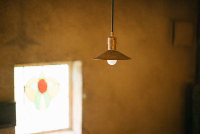 Close-up of illuminated pendant light hanging on wall at home