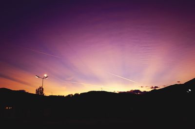 Silhouette vapor trail against sky during sunset