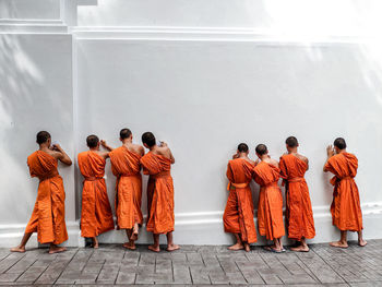 Rear view of monks standing against wall