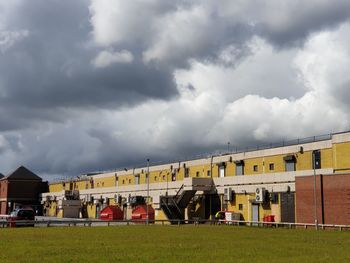 Buildings on field against cloudy sky