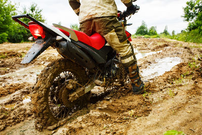 Low section of man riding motorcycle on dirt road