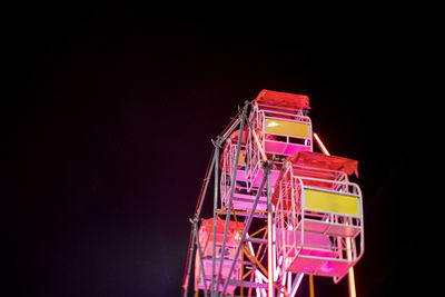 Low angle view of illuminated ferris wheel against black background