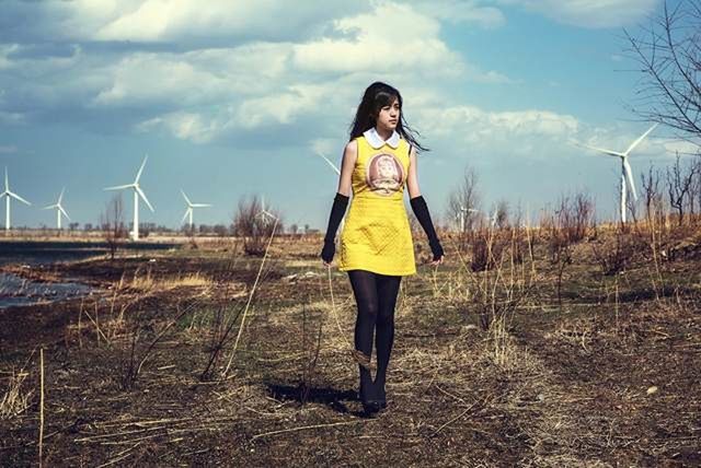 fuel and power generation, renewable energy, environmental conservation, one person, wind turbine, sky, full length, turbine, alternative energy, environment, wind power, standing, nature, young adult, women, young women, lifestyles, casual clothing, land, day, hair, outdoors, hairstyle, beautiful woman