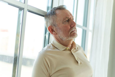 Thoughtful young man looking through window