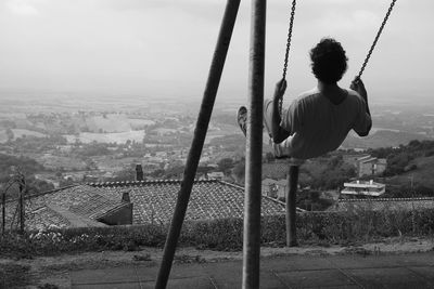 Rear view of man looking at cityscape against sky