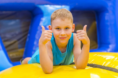 Portrait of cute smiling boy sitting on bouncy castle