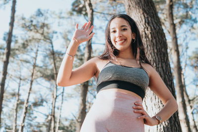 Portrait of young woman standing against trees