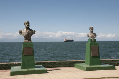 Statue by sea against sky