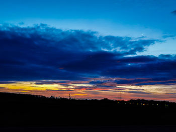 Silhouette landscape against dramatic sky during sunset