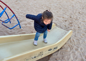 Young girl having fun jumping from a beach playground structure