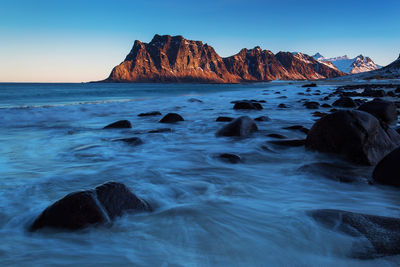 Scenic view of rocks in sea against clear sky