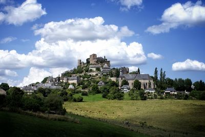 Houses on landscape against cloudy sky