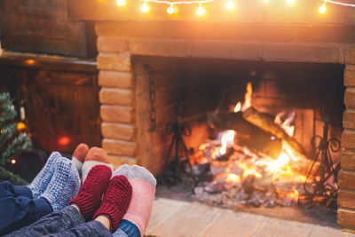 Low section of people by fireplace at home