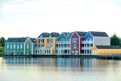 Row of colourful wooden dutch houses surrounded by lake de rietplas in houten, netherlands.