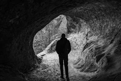 Rear view of silhouette mid adult man standing in cave