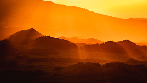 Orange and yellow colors, sunrise over island, mountains with sun rays.
