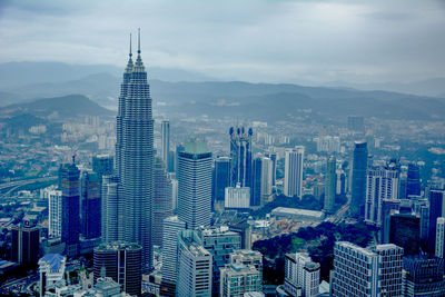 Aerial view of cityscape against cloudy sky