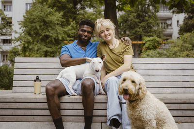 Portrait of smiling heterosexual couple with dogs in public park