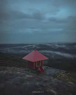 Red flag on building by mountain against sky