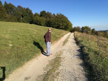 Rear view of man walking on road against clear sky