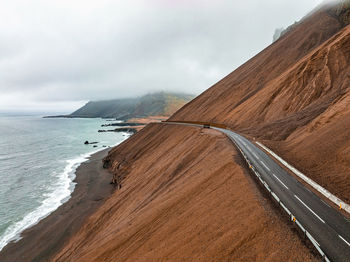 Endless road into the cloudy mountains and hills of iceland during sunny cloudy weather.