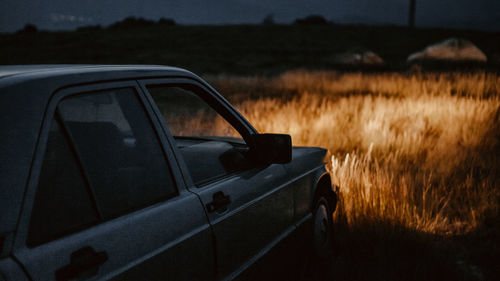 Car on road by field against sky