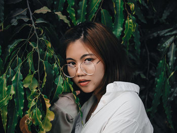 Portrait of beautiful young woman by tree